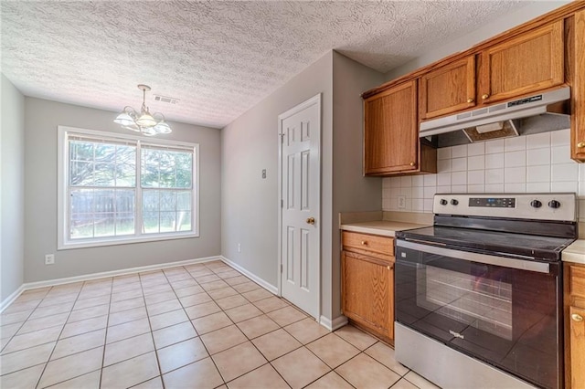 647 New England Way, Lawrenceville, GA 30046 - kitchen with stainless steel electric stove, under cabinet range hood, brown cabinetry, decorative backsplash, and a chandelier
