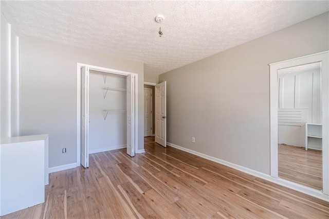 647 New England Way, Lawrenceville, GA 30046 - unfurnished bedroom featuring light wood-type flooring, a closet, a textured ceiling, and baseboards
