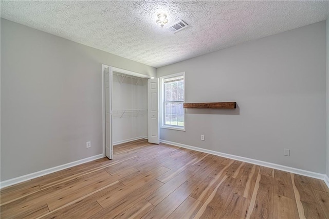 647 New England Way, Lawrenceville, GA 30046 - unfurnished bedroom with wood-type flooring, baseboards, a closet, and a textured ceiling