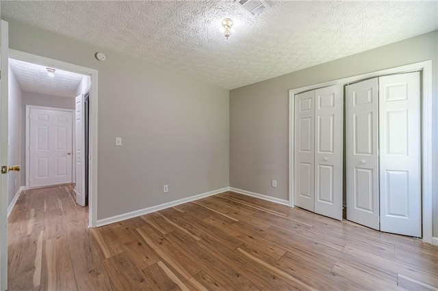 647 New England Way, Lawrenceville, GA 30046 - unfurnished bedroom featuring light wood-style floors, a textured ceiling, baseboards, and a closet