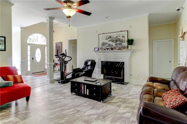 living room with ceiling fan, ornate columns, crown molding, and a high end fireplace