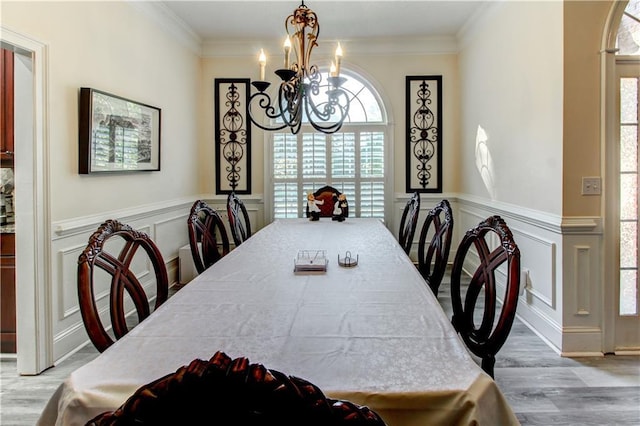 dining space with light hardwood / wood-style floors, ornamental molding, and a chandelier