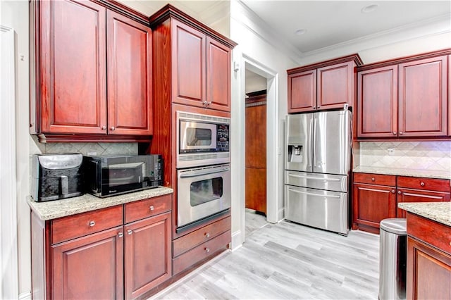 kitchen with tasteful backsplash, light stone counters, light hardwood / wood-style flooring, crown molding, and appliances with stainless steel finishes