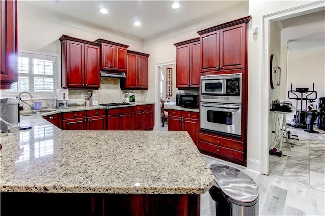 kitchen featuring appliances with stainless steel finishes, tasteful backsplash, light stone counters, and a breakfast bar area