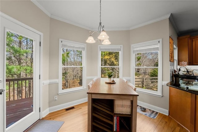 dining room featuring baseboards, visible vents, light wood finished floors, ornamental molding, and a wealth of natural light