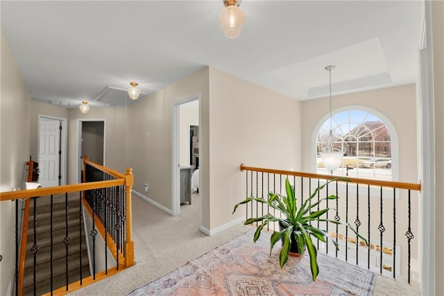 corridor featuring an upstairs landing, a tray ceiling, baseboards, and carpet floors