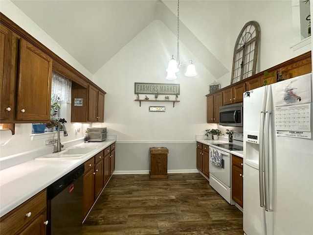 kitchen with dark wood-type flooring, sink, vaulted ceiling, hanging light fixtures, and stainless steel appliances