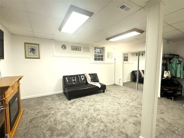 living area featuring a paneled ceiling and carpet