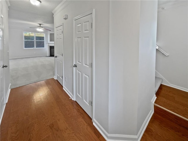 hallway with stairs, wood finished floors, and baseboards