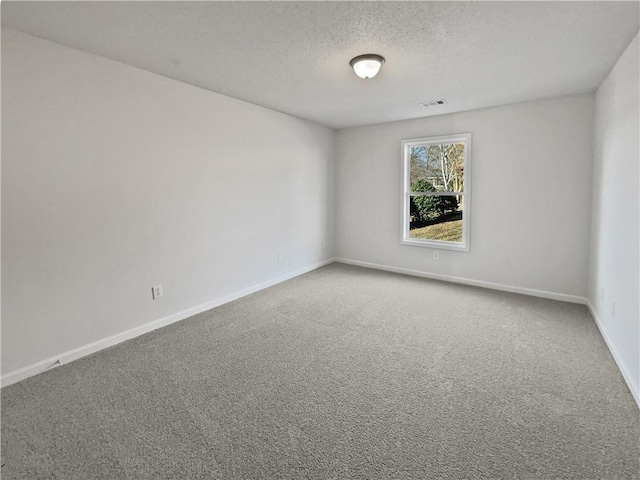 carpeted spare room with a textured ceiling, visible vents, and baseboards