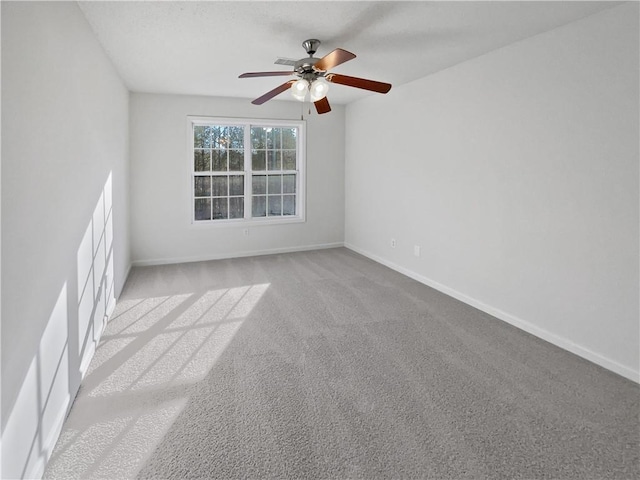 spare room featuring a ceiling fan, light colored carpet, and baseboards