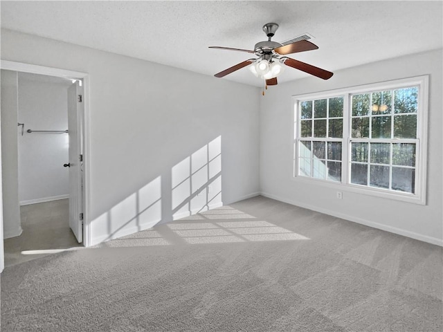 empty room featuring light colored carpet, ceiling fan, visible vents, and baseboards