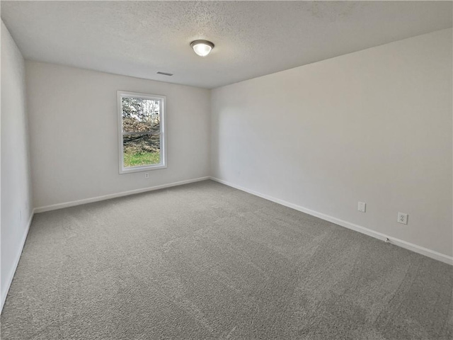 carpeted spare room featuring visible vents, baseboards, and a textured ceiling