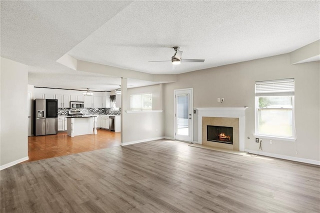 unfurnished living room featuring ceiling fan, a textured ceiling, and light hardwood / wood-style flooring