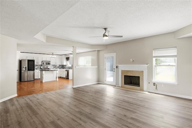 unfurnished living room with light hardwood / wood-style flooring, a textured ceiling, and ceiling fan