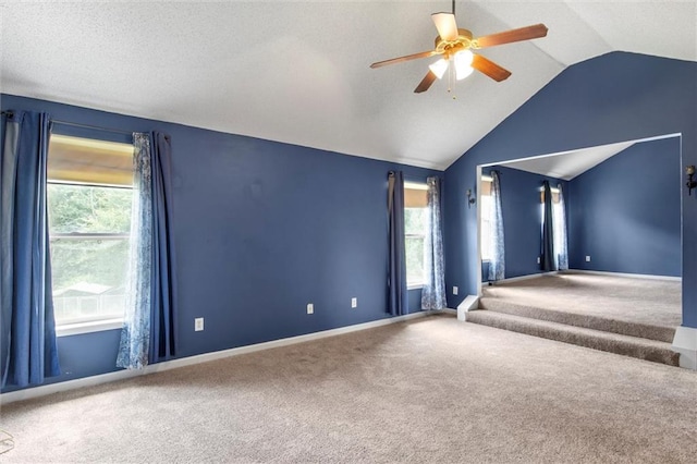 carpeted spare room with ceiling fan, vaulted ceiling, and a wealth of natural light