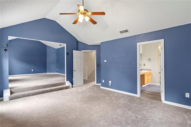 unfurnished bedroom featuring ensuite bathroom, carpet flooring, vaulted ceiling, and ceiling fan