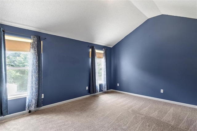 empty room with a textured ceiling, carpet flooring, and lofted ceiling