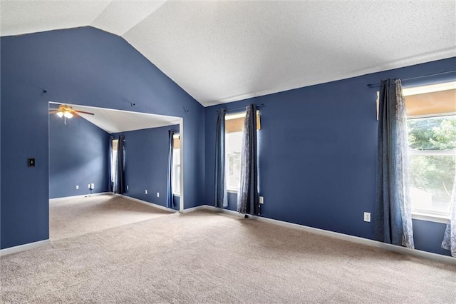 carpeted empty room featuring ceiling fan, a textured ceiling, and vaulted ceiling