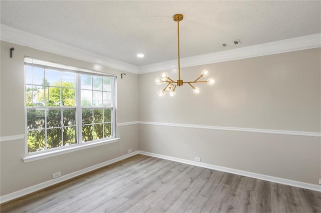 empty room with a notable chandelier, hardwood / wood-style floors, a textured ceiling, and crown molding