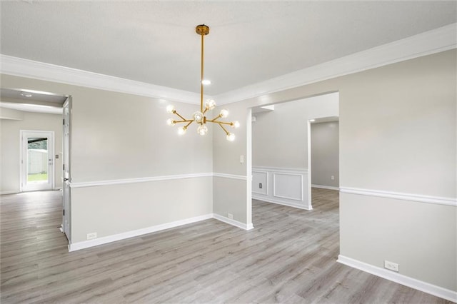 unfurnished dining area featuring ornamental molding, an inviting chandelier, and light wood-type flooring