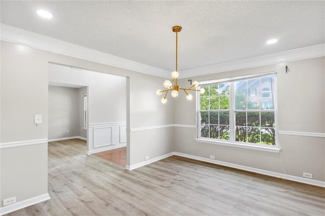 unfurnished room featuring light hardwood / wood-style floors, ornamental molding, a chandelier, and a textured ceiling