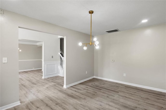 spare room with hardwood / wood-style flooring and a chandelier