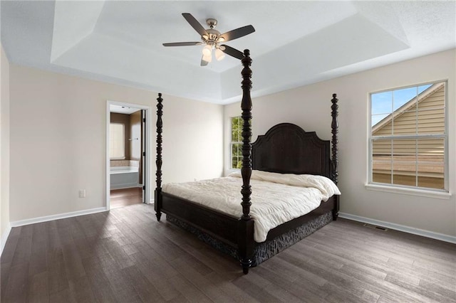 bedroom with a tray ceiling, wood finished floors, and baseboards