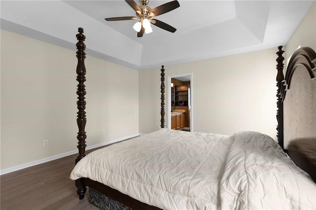 bedroom with a raised ceiling, wood finished floors, baseboards, and a ceiling fan