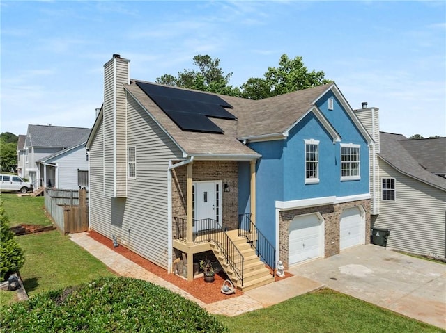 split level home featuring a chimney, driveway, solar panels, a garage, and brick siding