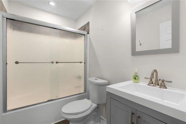 full bath featuring toilet, shower / bath combination with glass door, and vanity