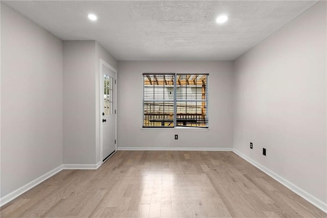 spare room featuring light wood-style floors, recessed lighting, and baseboards