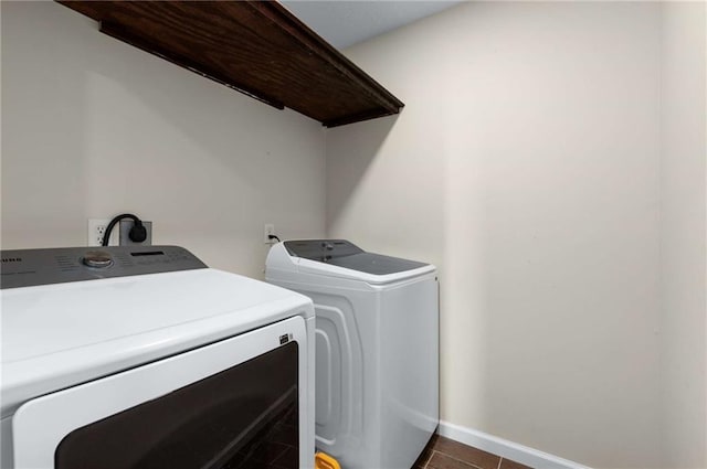 washroom with washing machine and dryer, baseboards, and dark tile patterned flooring