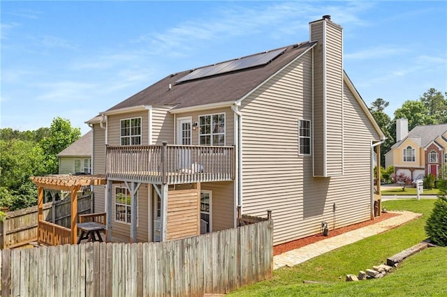 rear view of property featuring solar panels, a chimney, and a pergola