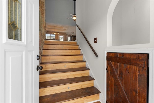 stairway featuring arched walkways and ceiling fan