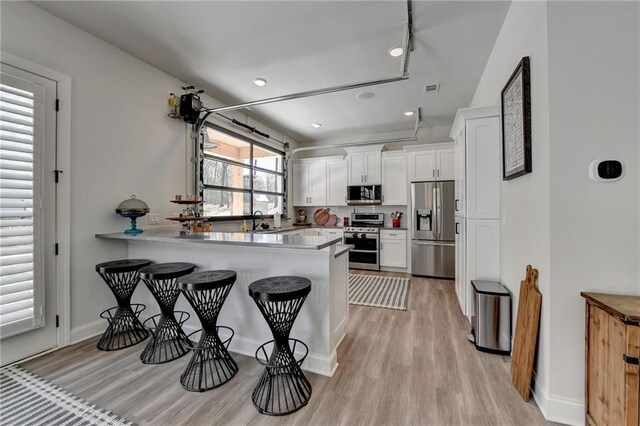 132 Swift Creek Way, Jefferson, GA 30549 - kitchen featuring kitchen peninsula, appliances with stainless steel finishes, sink, light hardwood / wood-style floors, and white cabinetry