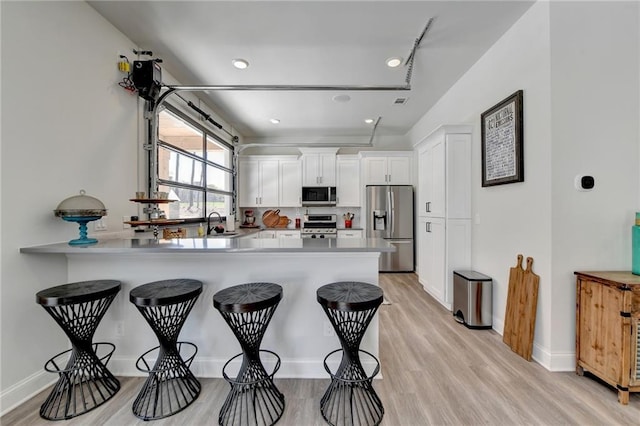 132 Swift Creek Way, Jefferson, GA 30549 - kitchen with kitchen peninsula, appliances with stainless steel finishes, white cabinetry, and a kitchen breakfast bar