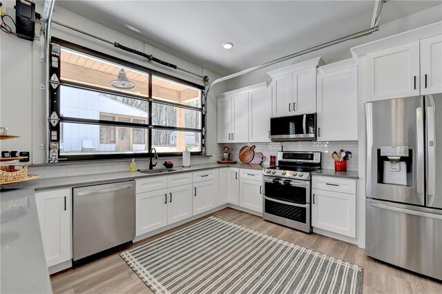 132 Swift Creek Way, Jefferson, GA 30549 - kitchen with decorative backsplash, appliances with stainless steel finishes, sink, light hardwood / wood-style floors, and white cabinetry