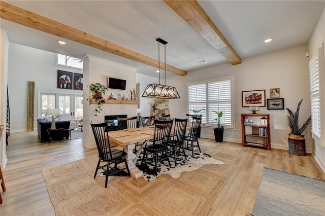 132 Swift Creek Way, Jefferson, GA 30549 - dining room with beamed ceiling, light wood-type flooring, a brick fireplace, and a healthy amount of sunlight