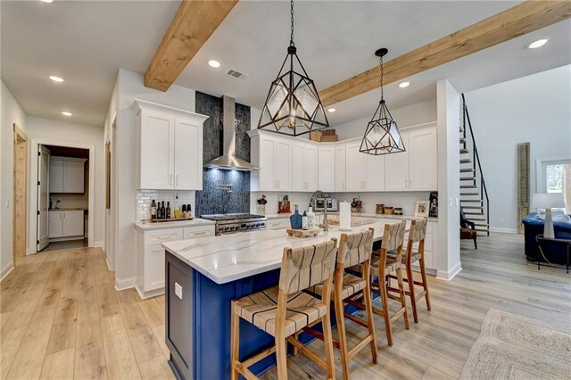 132 Swift Creek Way, Jefferson, GA 30549 - kitchen featuring wall chimney exhaust hood, a breakfast bar, range, white cabinetry, and an island with sink