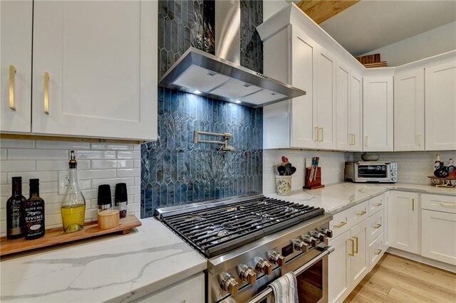 132 Swift Creek Way, Jefferson, GA 30549 - kitchen with light stone countertops, backsplash, wall chimney exhaust hood, high end stove, and white cabinetry