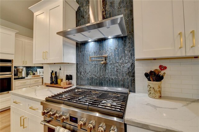 132 Swift Creek Way, Jefferson, GA 30549 - kitchen featuring white cabinetry, light stone countertops, wall chimney range hood, and stainless steel appliances