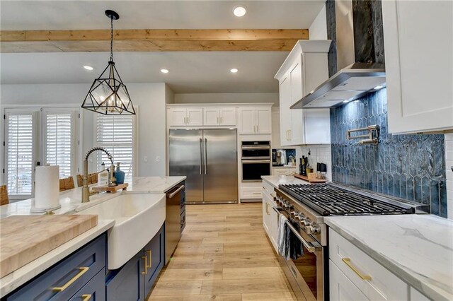 132 Swift Creek Way, Jefferson, GA 30549 - kitchen featuring blue cabinetry, premium appliances, white cabinetry, and wall chimney range hood