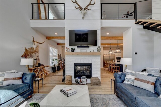 132 Swift Creek Way, Jefferson, GA 30549 - living room with beamed ceiling, wood-type flooring, ceiling fan with notable chandelier, and a brick fireplace