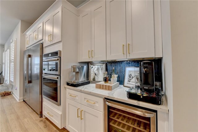 132 Swift Creek Way, Jefferson, GA 30549 - kitchen featuring white cabinets, wine cooler, appliances with stainless steel finishes, tasteful backsplash, and light stone counters