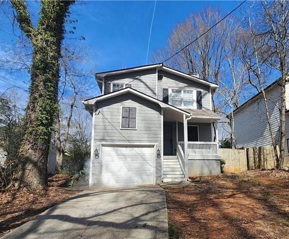 traditional-style home with concrete driveway, a porch, an attached garage, and fence