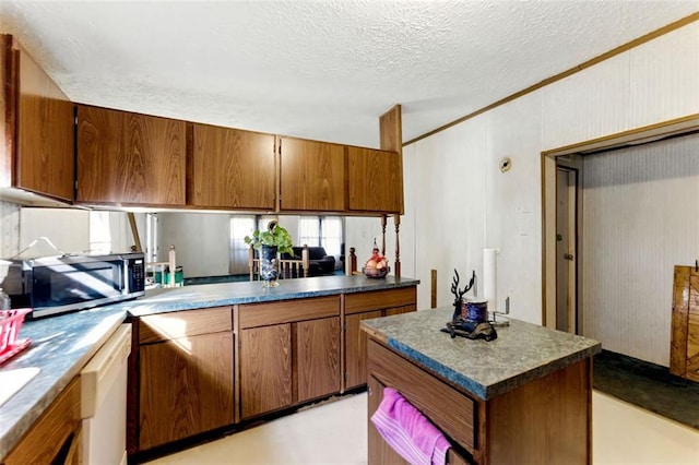 kitchen with dark countertops, stainless steel microwave, and brown cabinetry