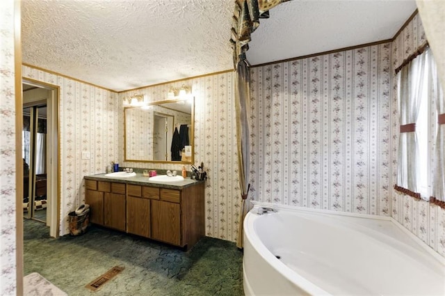 bathroom with a garden tub, a sink, a textured ceiling, and wallpapered walls