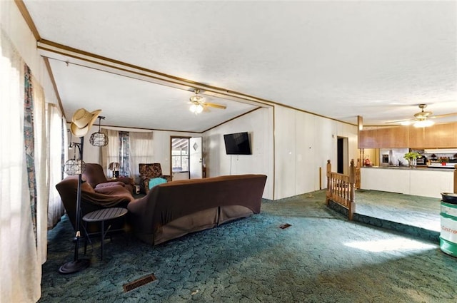 carpeted living area featuring ornamental molding, vaulted ceiling, visible vents, and ceiling fan