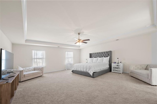 bedroom featuring a ceiling fan, carpet, a tray ceiling, and baseboards